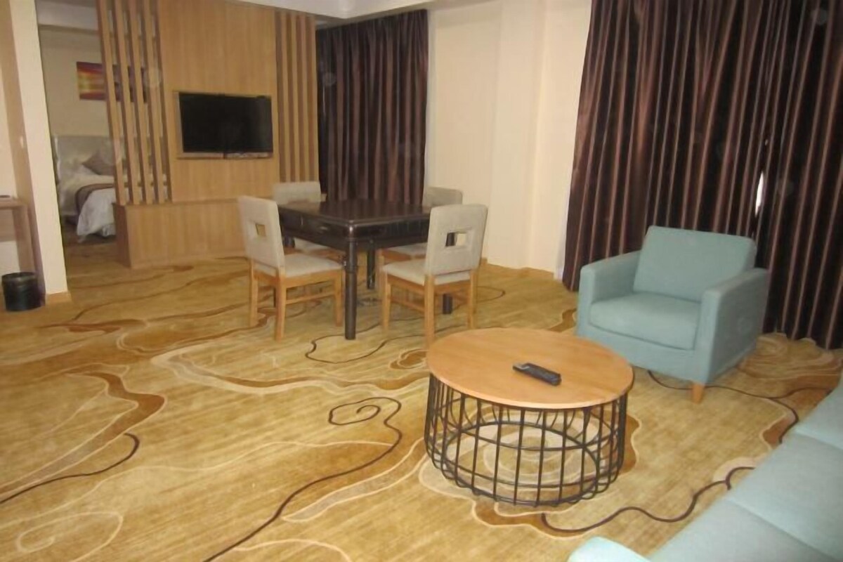 Ein Wohnzimmer mit rundem Couchtisch, einer Couch und einem Essbereich mit Stühlen und einem Tisch.
