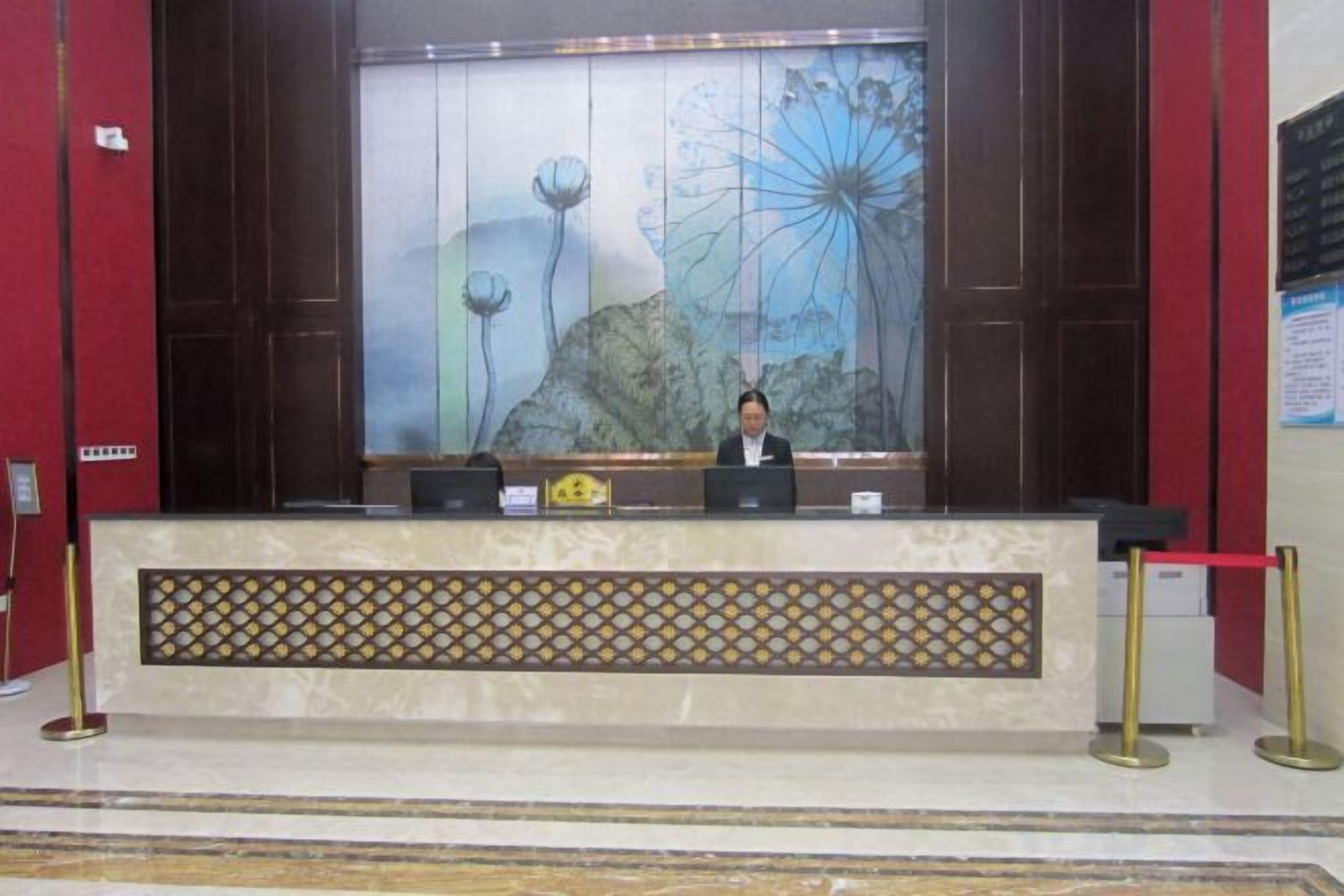 A reception desk with a large floral mural, a nameplate, and a red barrier.