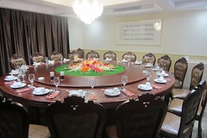 A round table with chairs, a floral centerpiece, and a whiteboard with text on the wall. - Yushi Culture City Hotel (Songyang)