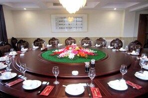 A conference room with a round table, chairs, and a floral centerpiece. - Yushi Culture City Hotel (Songyang)