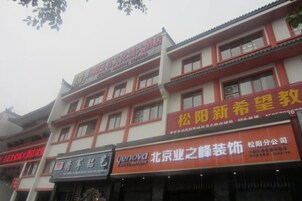 Un edificio de varios pisos con señalización comercial, incluyendo un negocio llamado 'Yenova' y otro con caracteres chinos.