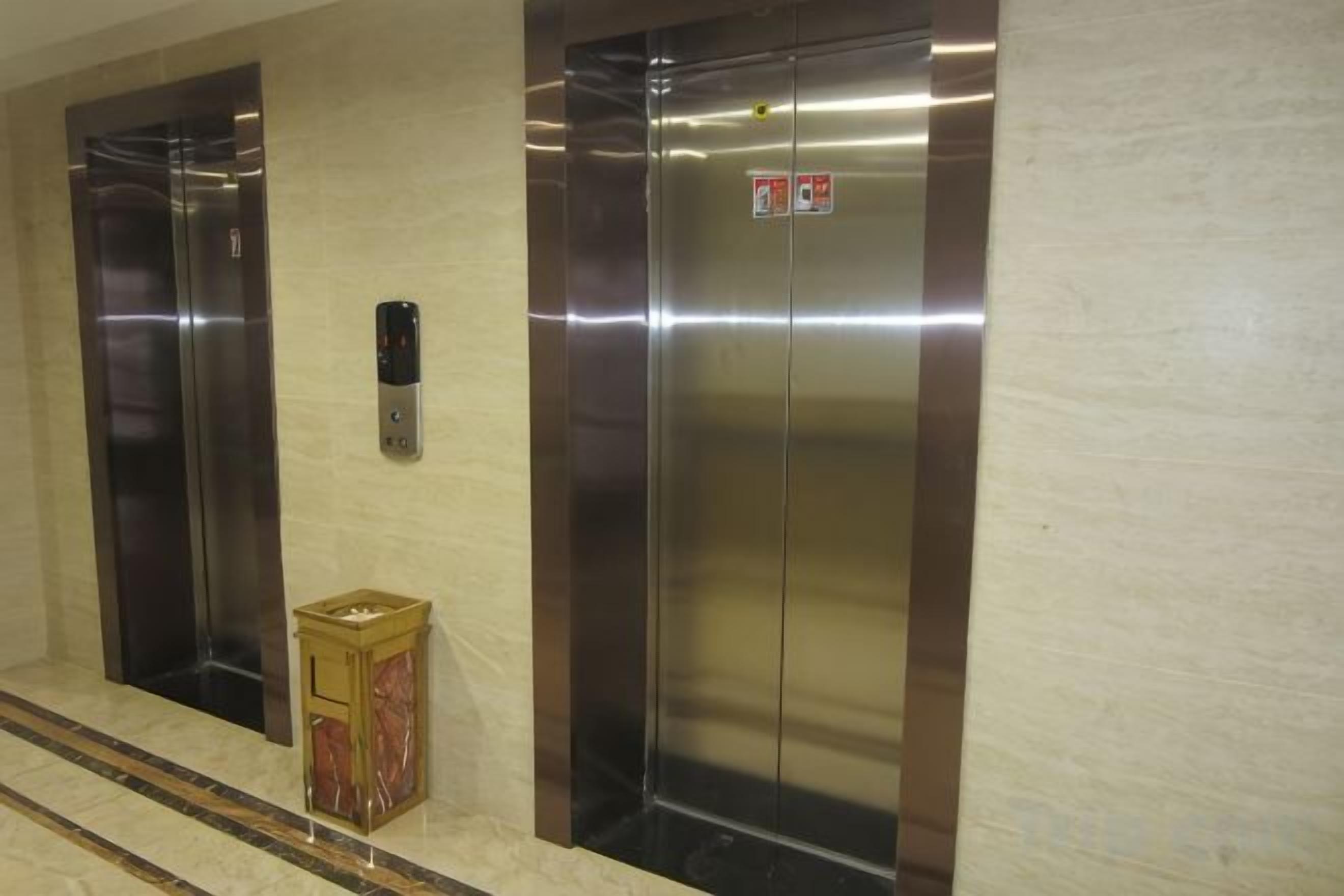 Deux ascenseurs équipés d’un panneau de commande et d’un panneau indiquant le système d’alarme incendie.