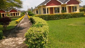 A row of single-story houses with a central pathway, surrounded by well-maintained lawns and hedges. - Lomanira Splendour (Mogotio)