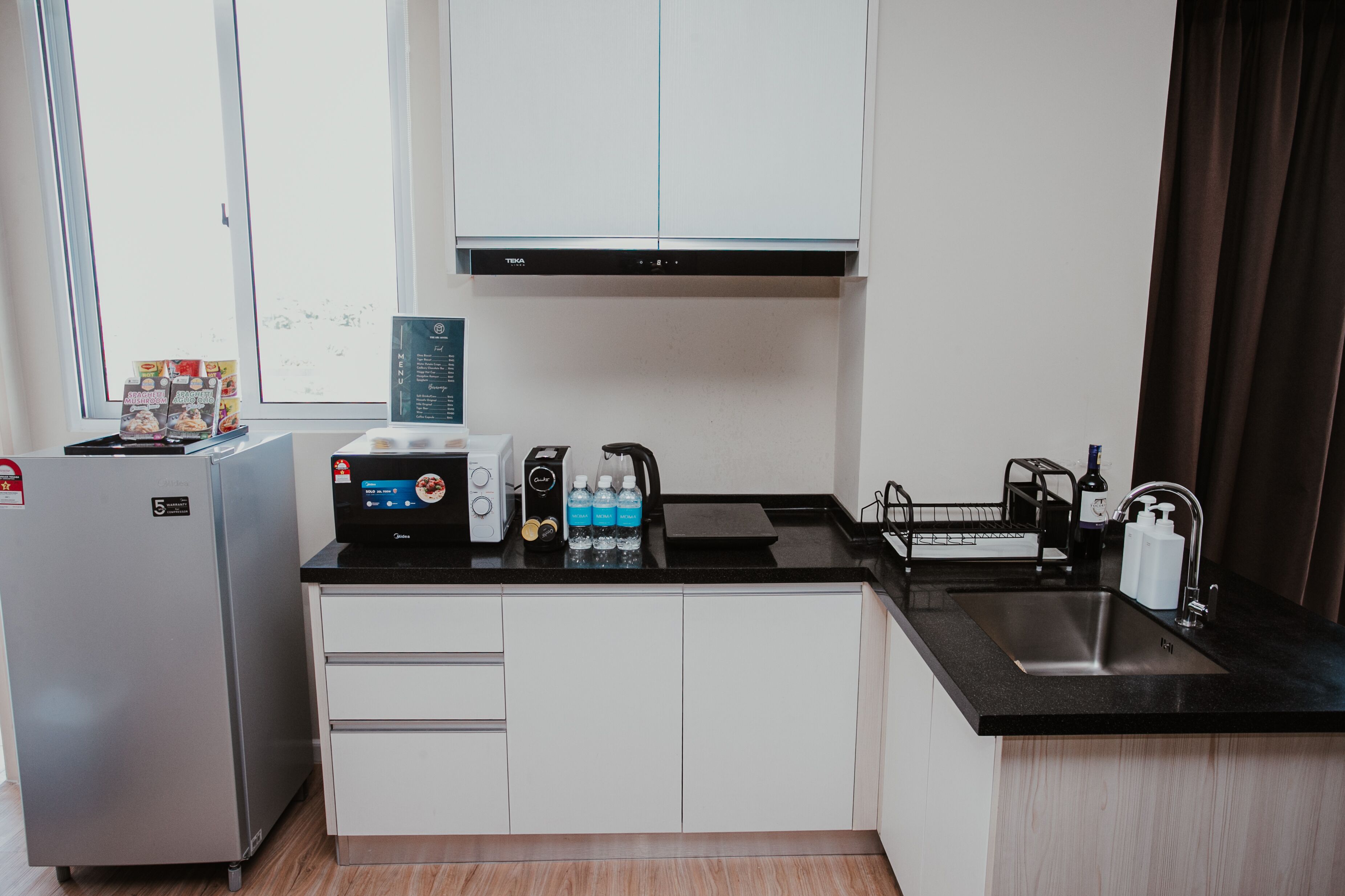 A compact kitchen with a refrigerator, a coffee maker, a toaster, and a sink.