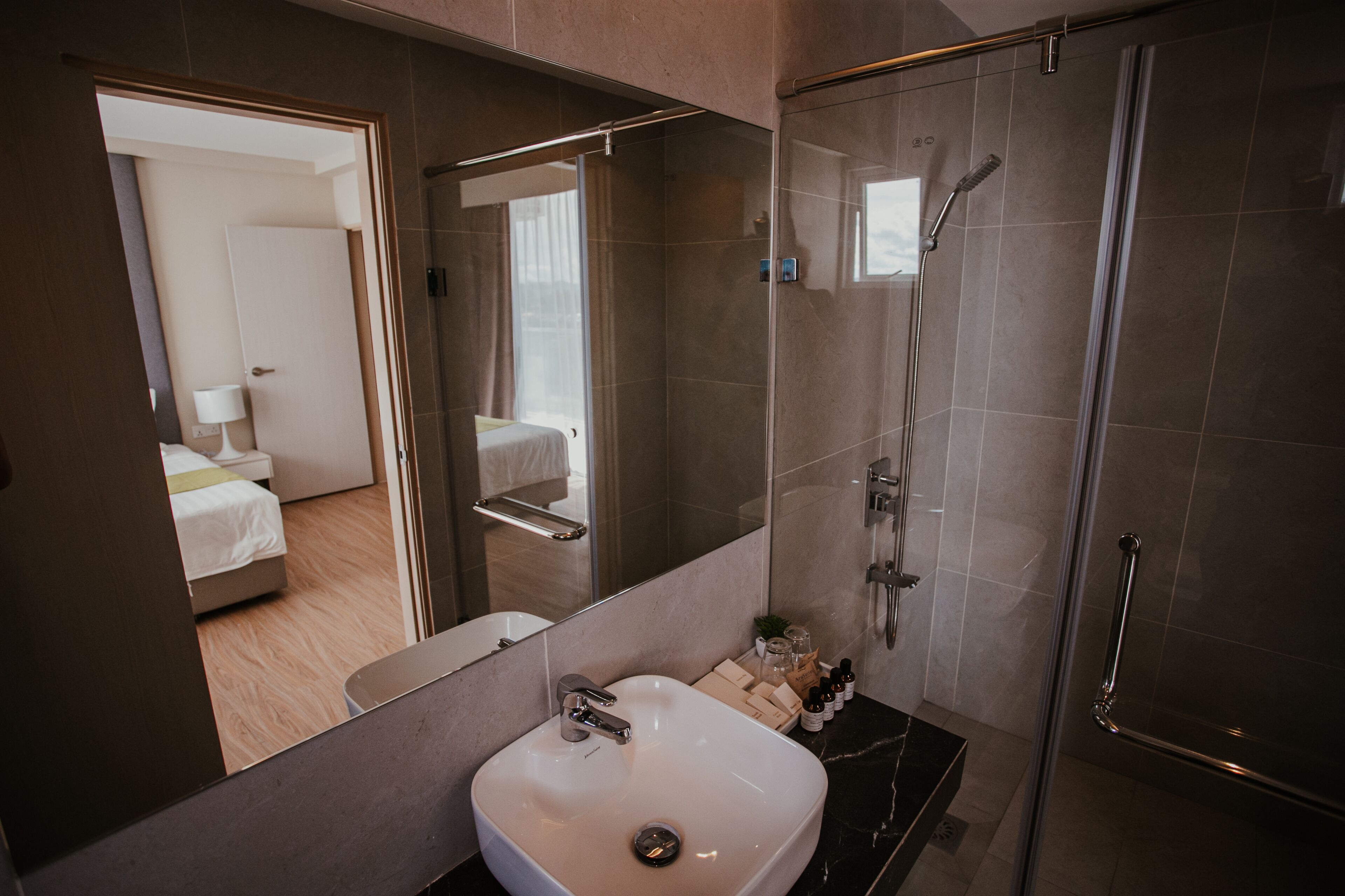 A modern bathroom with a large mirror, a sink, and a shower.