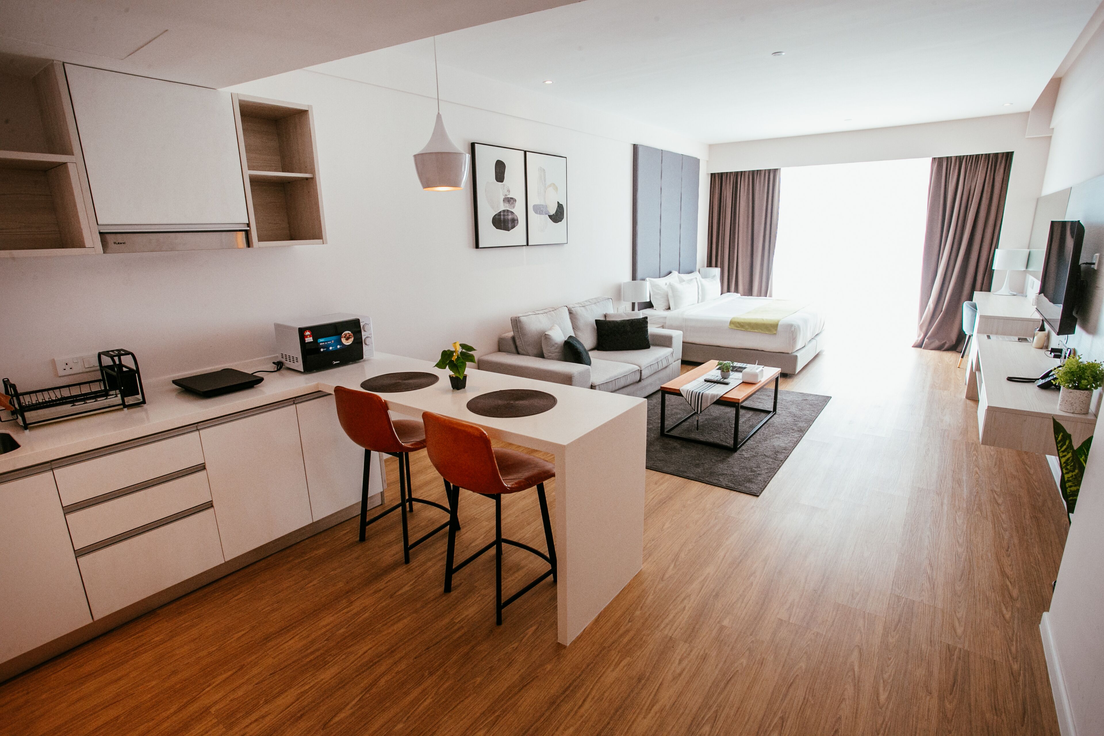A modern apartment with a kitchen, dining area, and living room. It includes a sofa, a coffee table, and a TV.