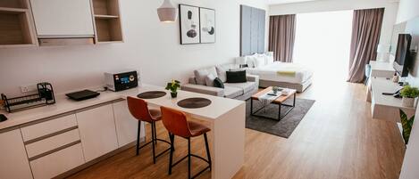 A modern apartment with a kitchen, dining area, and living room. It includes a sofa, a coffee table, and a TV.