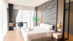 A modern hotel room with a large bed, a desk, and a chair. - The Aru Hotel, Aru Suites by Ayuhouz (Kota Kinabalu)