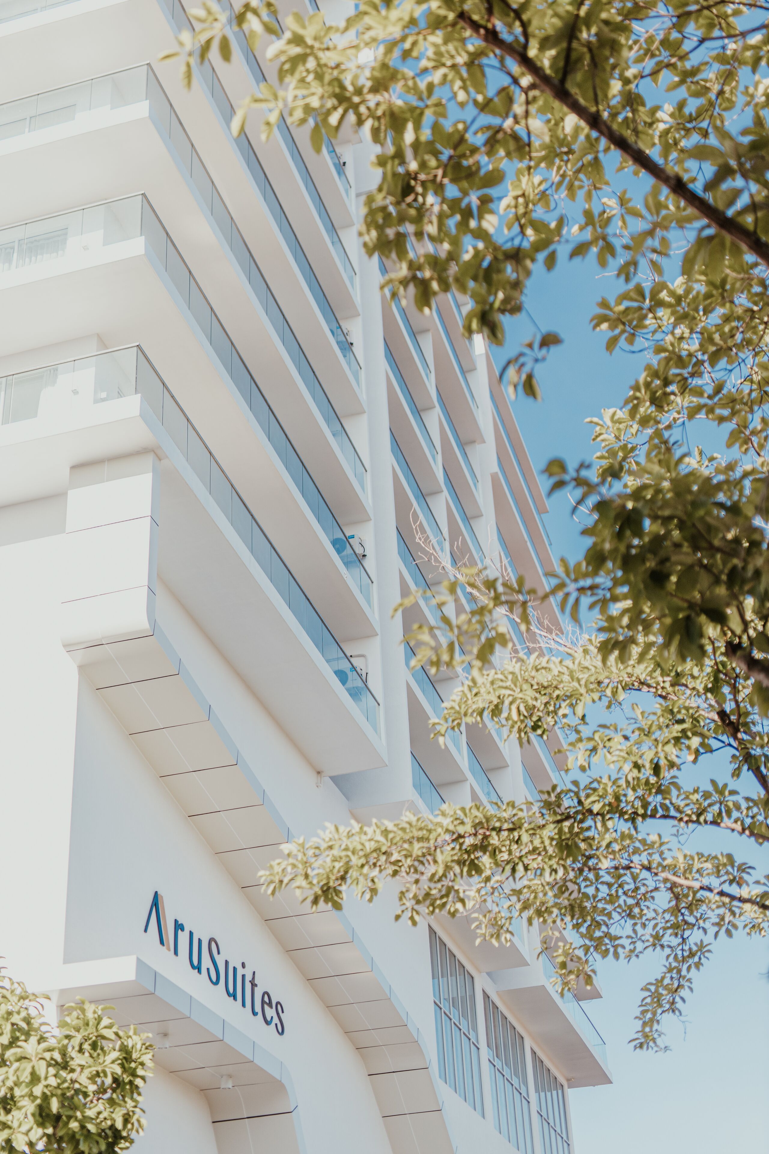 A modern hotel building with the name 'AruSuites' prominently displayed.