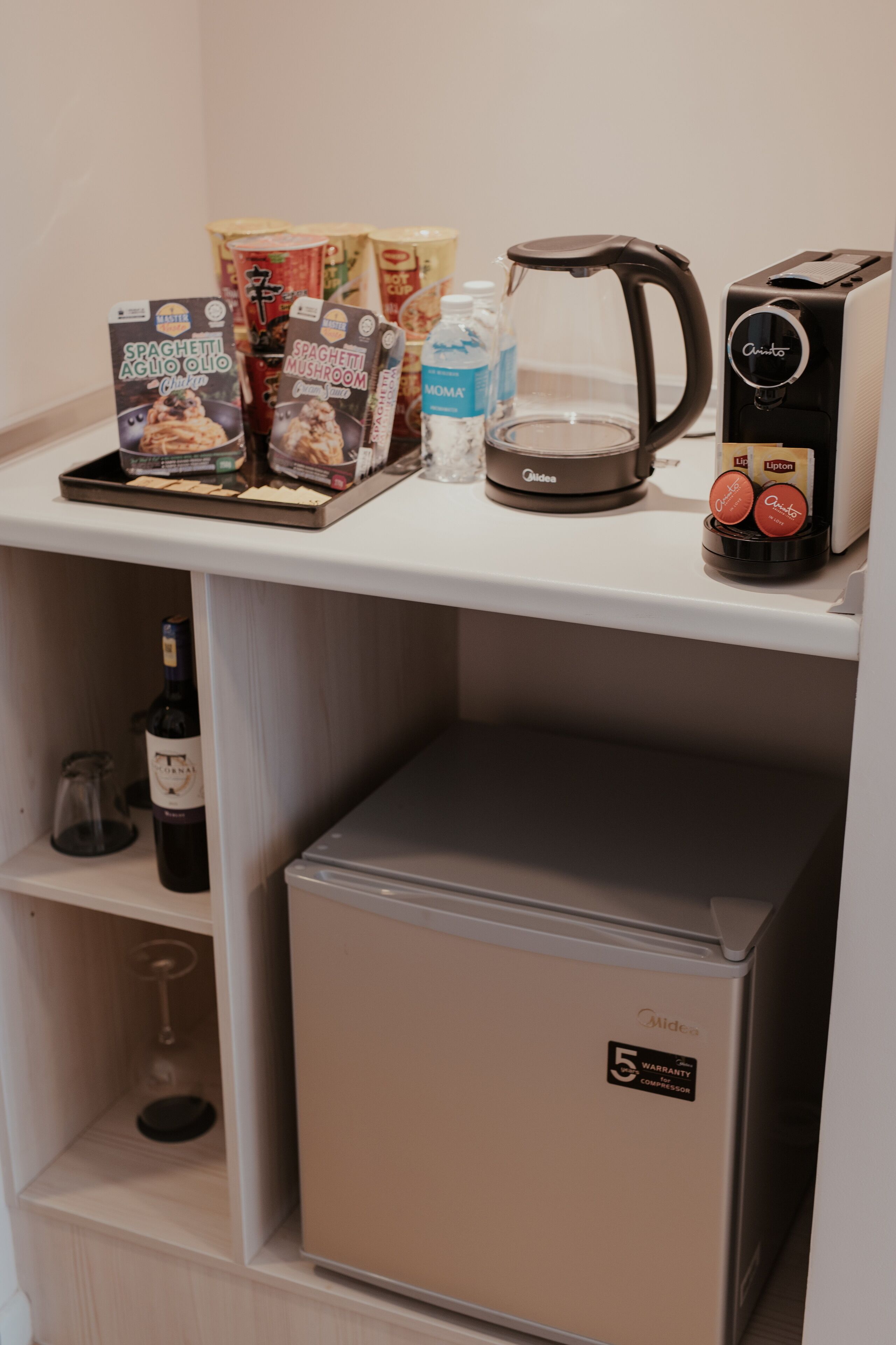 A kitchenette with a coffee maker, toaster, and packaged food items.