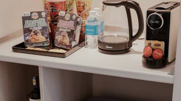 A kitchenette with a coffee maker, toaster, and packaged food items.