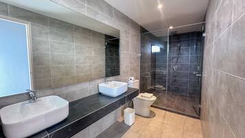 A modern bathroom with a large mirror, two sinks, a shower, and a toilet.