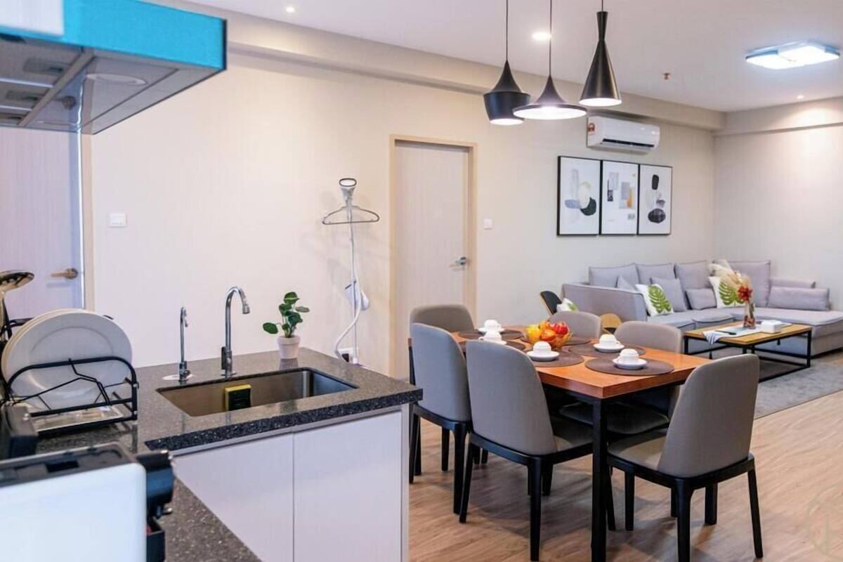 A modern kitchen with a sink, a dining area with a table and chairs, and a living area with a sofa and a coffee table.