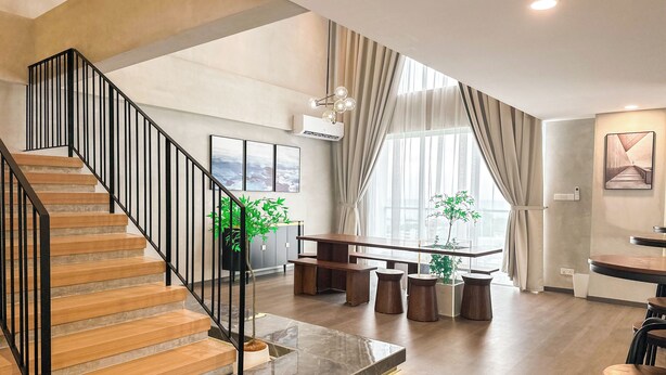 A modern interior with a wooden staircase, a dining area with stools, and a large window with curtains. - The Aru Hotel, Aru Suites by Ayuhouz (Kota Kinabalu)