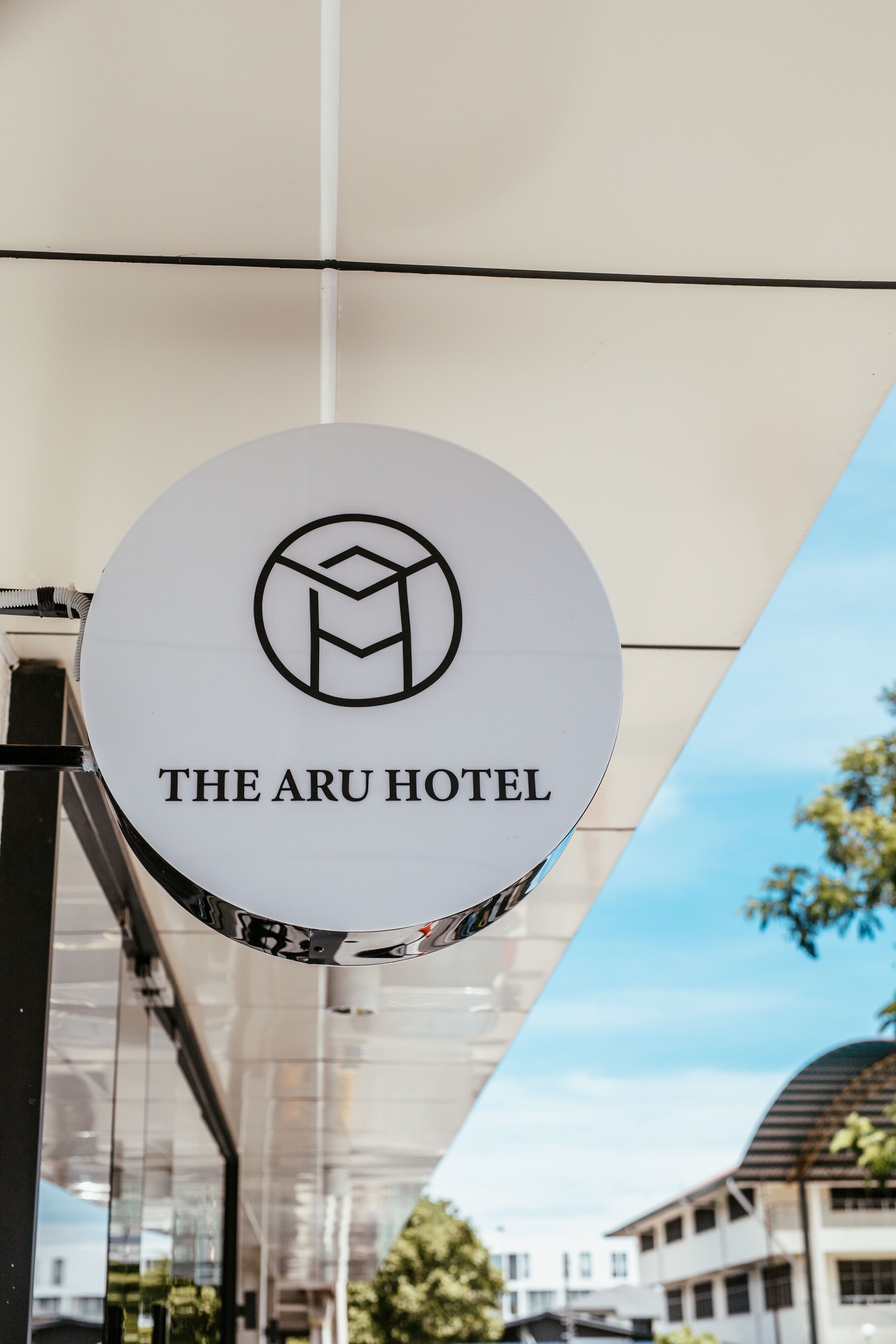 A circular sign with 'THE ARU HOTEL' text and a geometric logo.