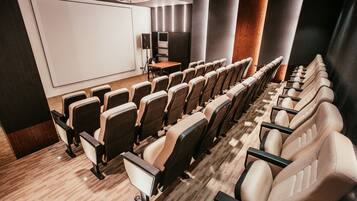 Una sala de cine moderna con filas de asientos cómodos, una pantalla grande y una cabina de proyección.