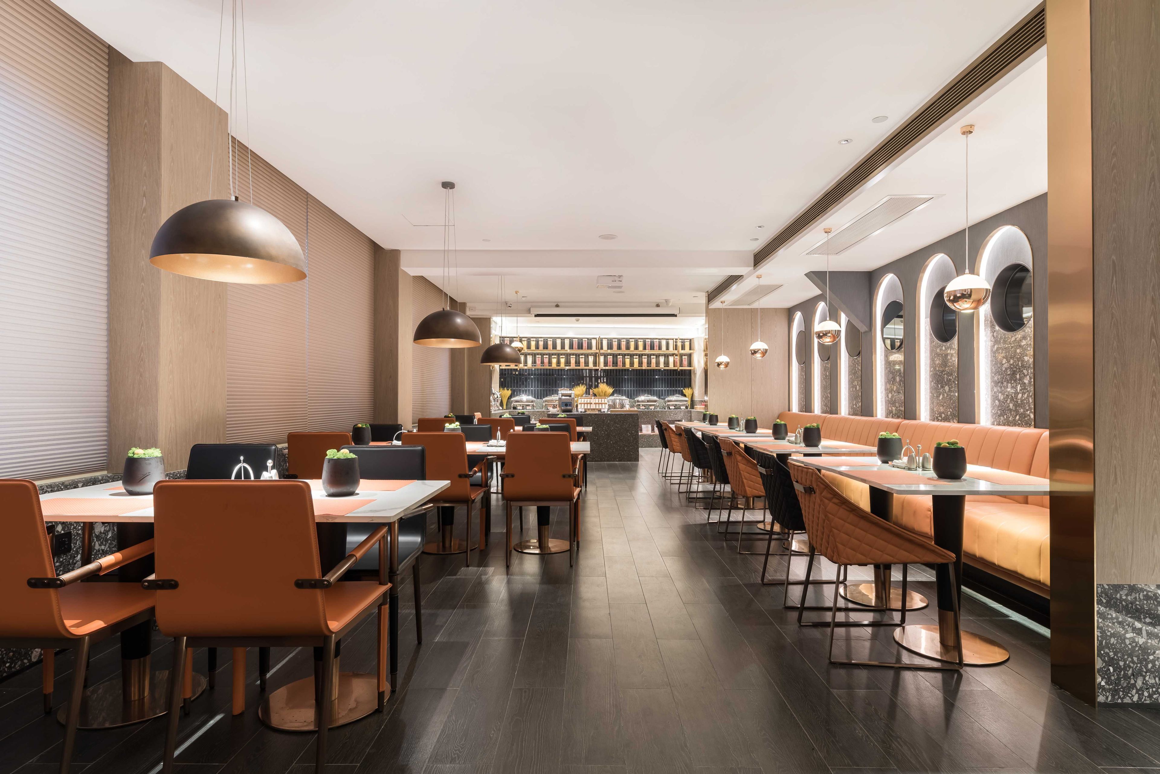 Een modern restaurant met lange gedeelde tafels en zitjes, een bar in het midden en een goed verlicht interieur.