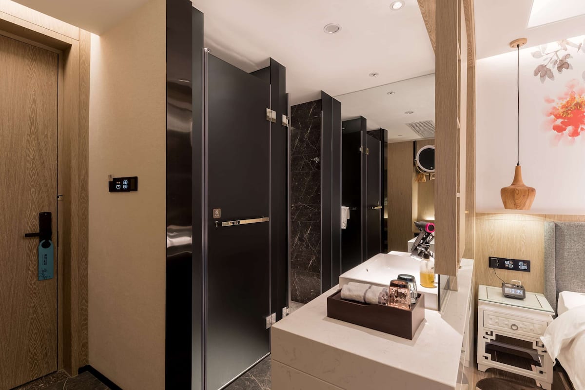 A modern hotel bathroom with a large mirror, a sink, and a vanity.