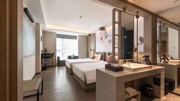 A modern hotel room with two beds, a large mirror, a vanity with a sink, and a desk with a chair.