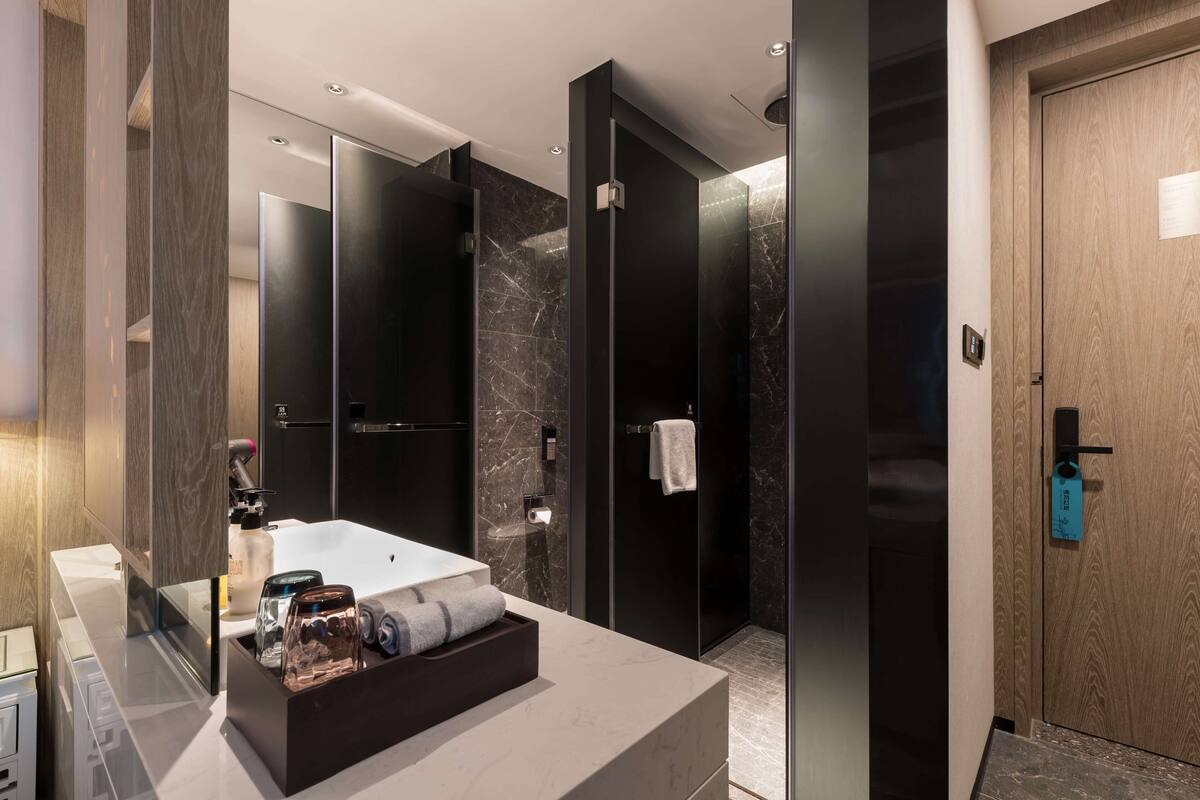 A modern bathroom with a large bathtub, a glass shower enclosure, and a wooden door.