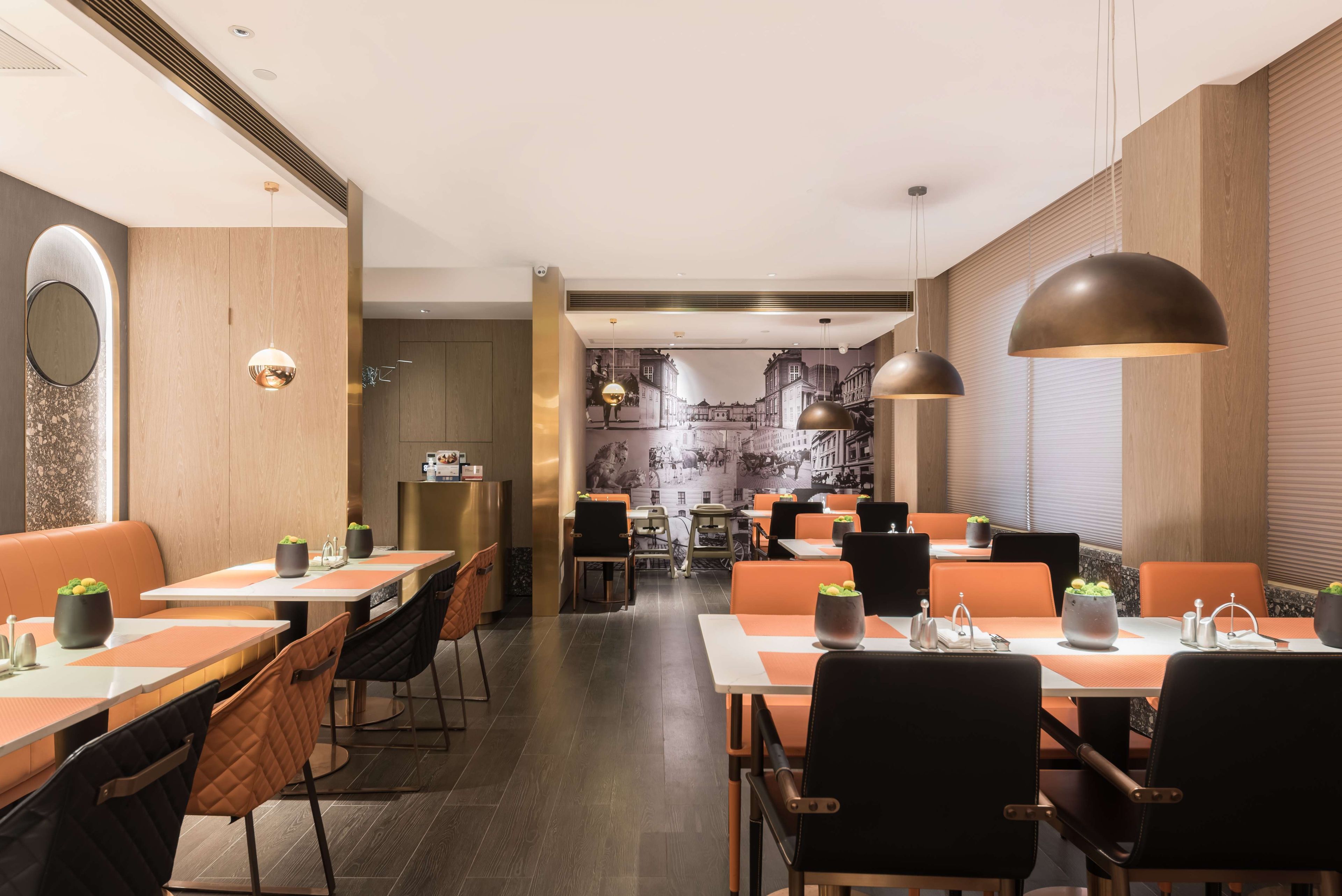 A modern restaurant with booths and tables, wooden accents, and pendant lighting.