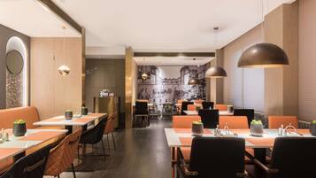 A modern restaurant with booths and tables, wooden accents, and pendant lighting.