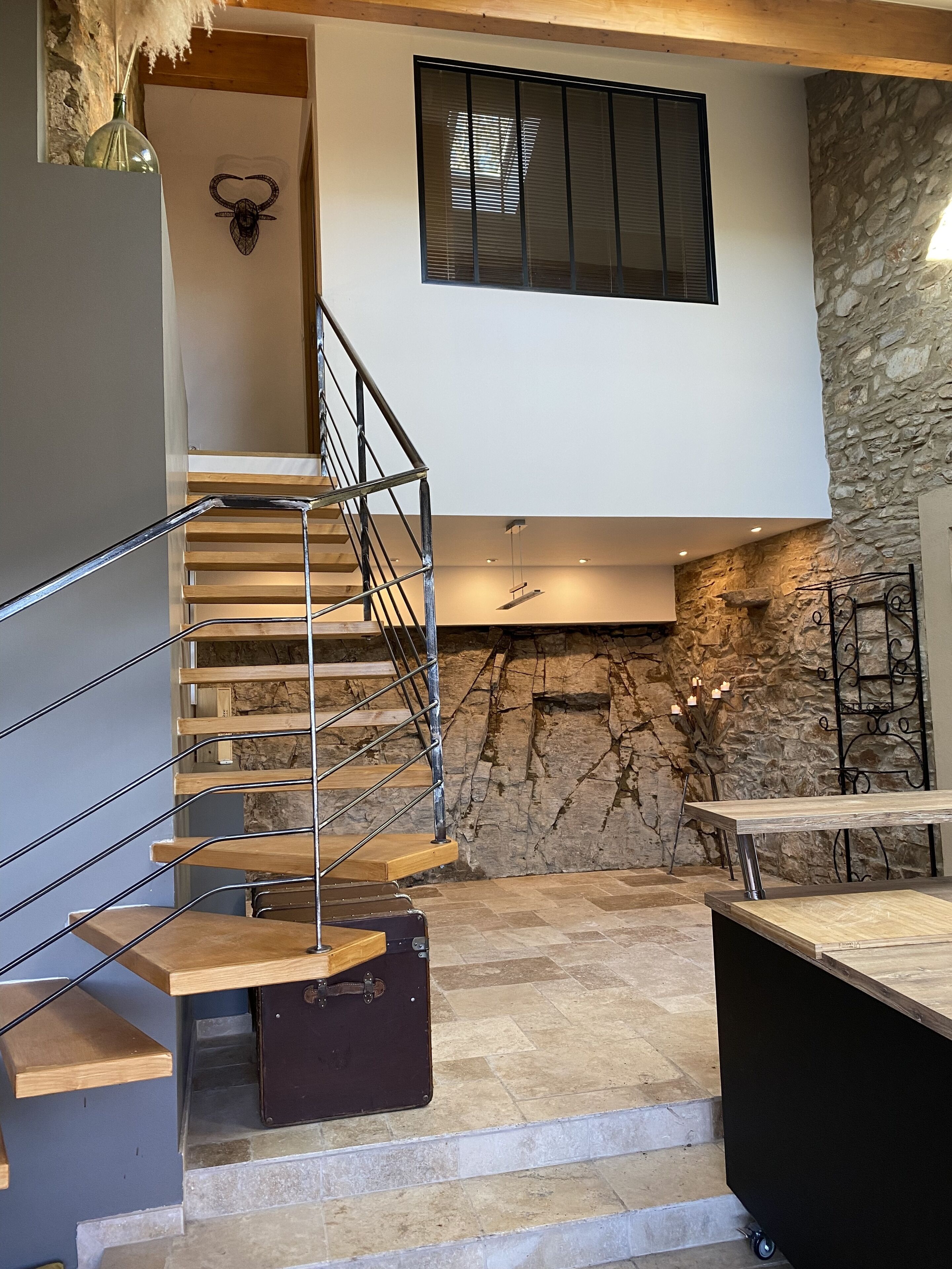 Un intérieur moderne avec un escalier en bois, un mur en pierre et des meubles aux lignes épurées.