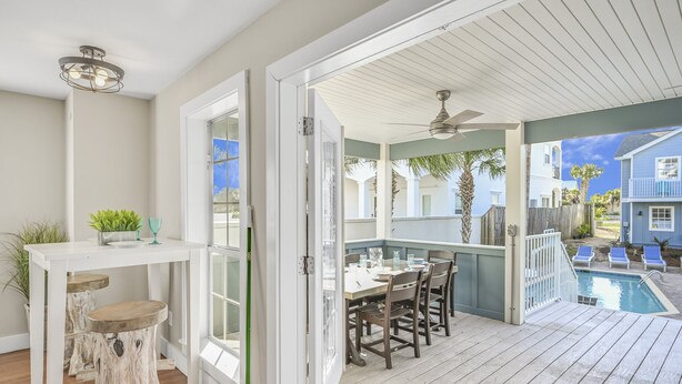 An open patio with a dining table and chairs, a pool, and a view of neighboring houses. - 7 BR, Gulf Views, Across From Beach, Movie Theater, Pool/Spa, Discount Golf Cart (Destin)