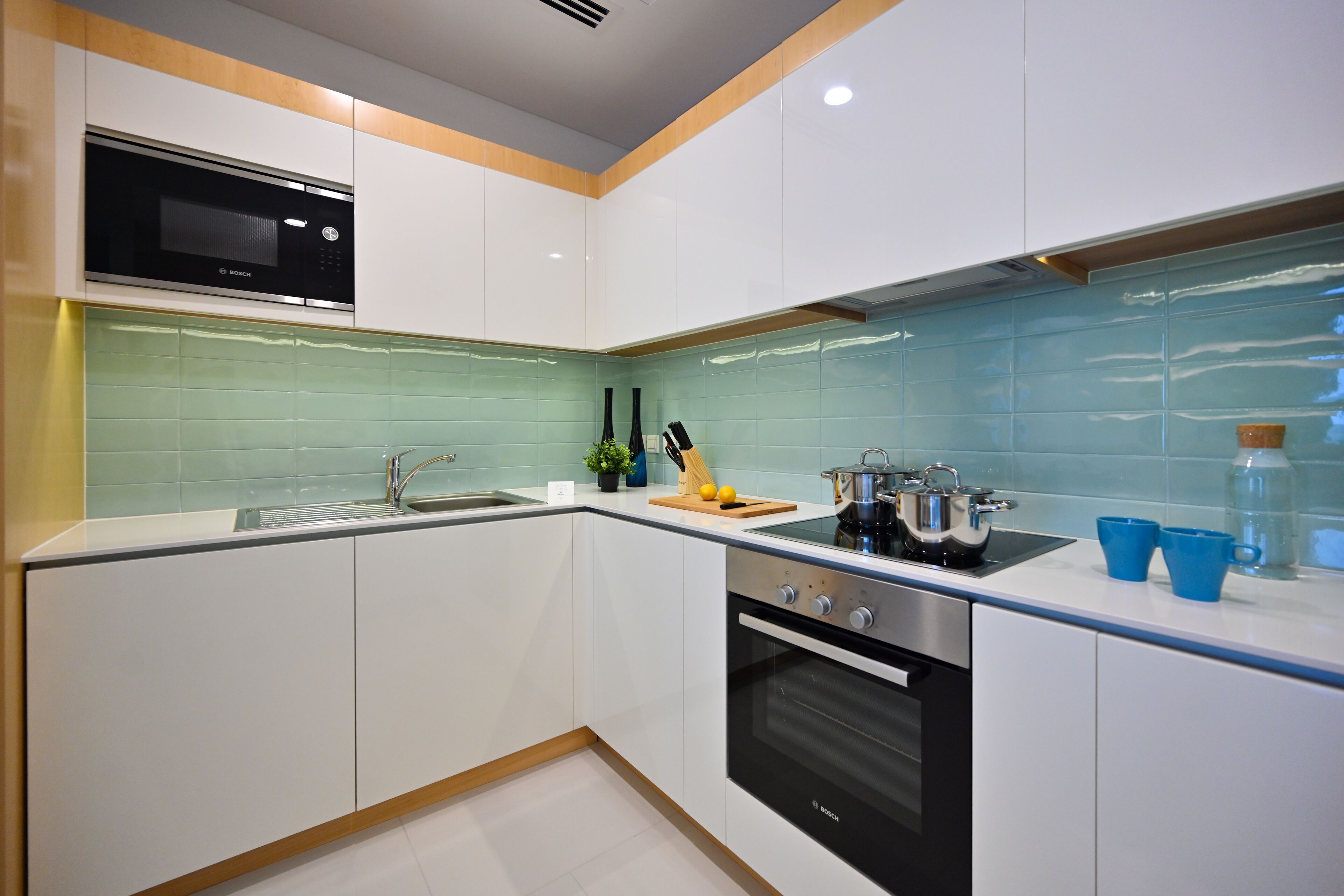 Una cocina moderna con armarios blancos, un microondas Bosch, un fregadero y una estufa.