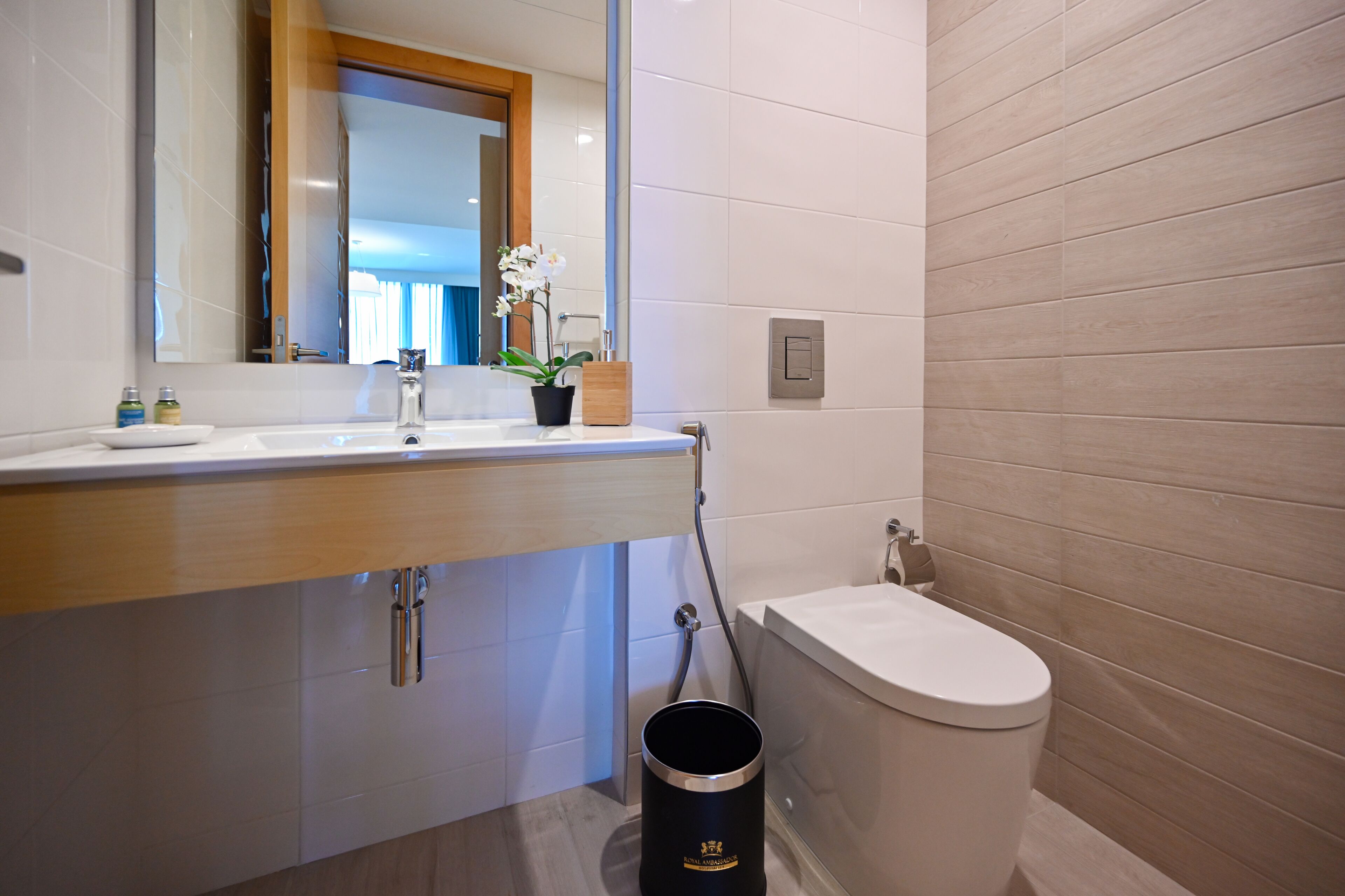A modern bathroom with a white sink, a mirror, a toilet, and a shower area.