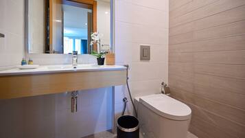 Un baño moderno con lavamanos blanco, un espejo, un inodoro y una zona de ducha.