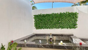 Zona de spa con mostrador de mármol, una botella de vodka Baikal, dos vasos y un frasco pequeño de loción.