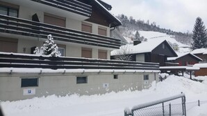 A building with multiple balconies and a snow-covered roof, surrounded by snow. - Elfe - Apartments Three-bedroom Apartment for 6 Guests With Patio (Emmetten)