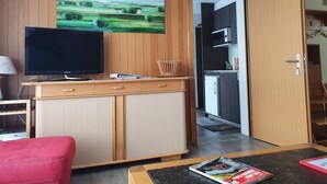 A modern living room with a flat-screen TV, wooden furniture, and a painting on the wall. - Elfe - Apartments Three-bedroom Apartment for 6 Guests With Patio (Emmetten)