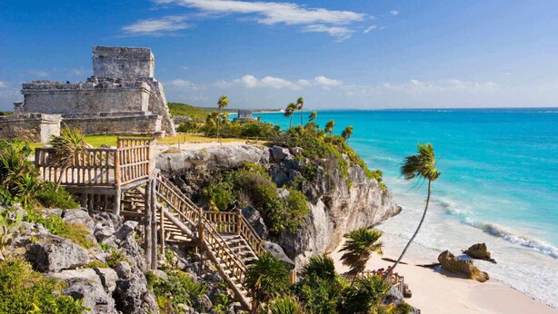 Une vue sur la côte, avec une structure en pierre, un escalier en bois et une plage.