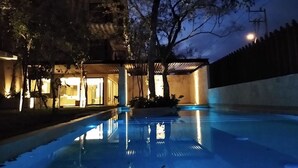 Une piscine au crépuscule, avec un bâtiment en arrière-plan.
