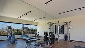 Une salle de sport moderne, équipée de matériel d’exercice, dotée de grandes fenêtres et offrant une vue sur l’extérieur.