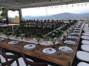 A long dining table set for a meal with a scenic mountain view in the background. - Quinta Joselito in Cuernavaca (Jiutepec)