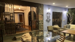 Un coin repas avec une table et des chaises en verre, un canapé et un élément décoratif mural.