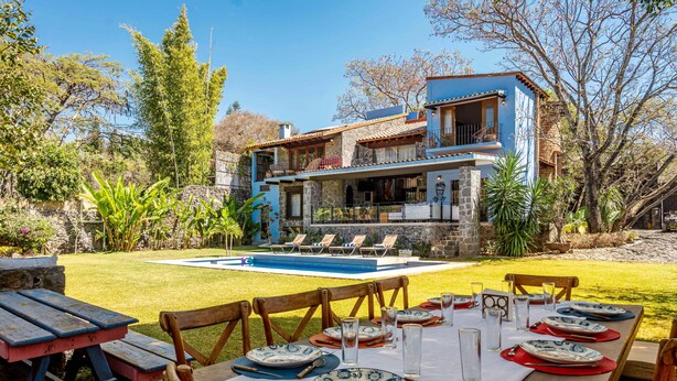 Un espace repas avec une piscine et une maison en arrière-plan.