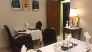 A dining area with a table set for four, chairs, a door, and three welcome signs on the wall. - Soeteweide North Bb - Close to Fancourt Golf Estate (George)