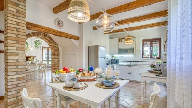 A spacious kitchen with white cabinetry, a central island with a fruit bowl, and hanging pendant lights.