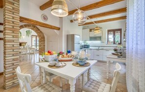 A spacious kitchen with white cabinetry, a central island with a fruit bowl, and hanging pendant lights.