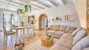 A spacious living area with a high ceiling, a dining table set for four, a sofa, and a coffee table.
