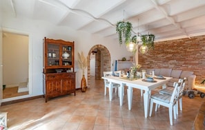 A dining area with a white table and chairs, a wooden cabinet, and a brick wall. - Villa Bentivoglio - Holiday Home With Swimming Pool (Montelupone)