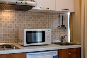 Una cocina con microondas, lavaplatos y alacena.
