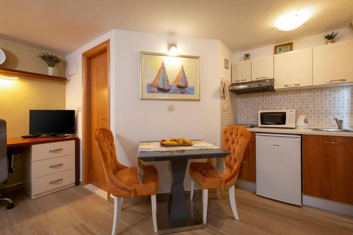 A compact kitchen with a dining table, chairs, a microwave, and a small refrigerator.