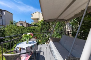 A balcony with a table, chairs, and a sofa under a canopy. - Studio Apartment Oleander (Split)