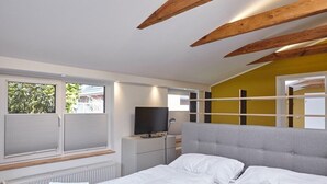 Een moderne slaapkamer met een bed, een televisie en een raam met zonwering.