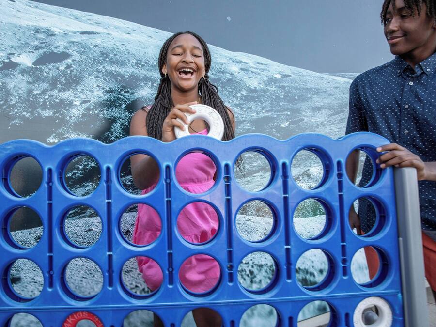 Uma barreira de plástico azul com recortes circulares, alguns dos quais contêm objetos rosa.